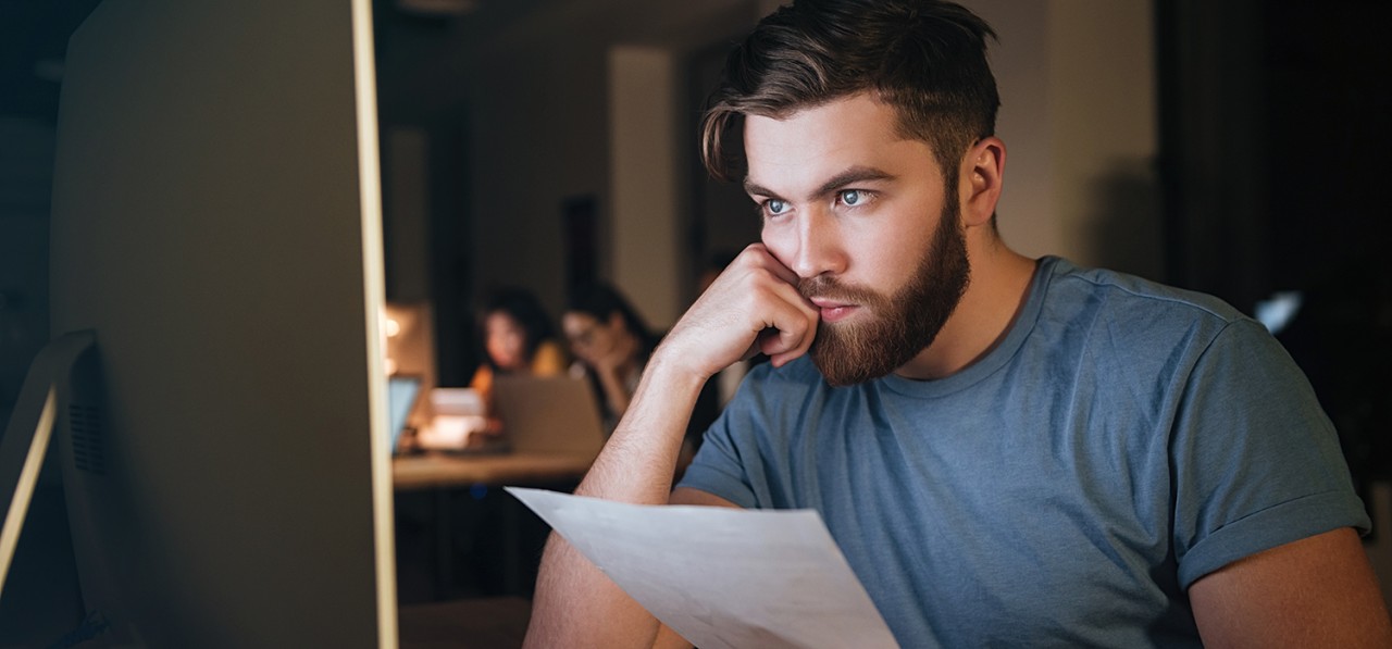 busy-caucasian-bearded-businessman-working-late-at-night-with-computer-looking-at-comp-SBI-302894196